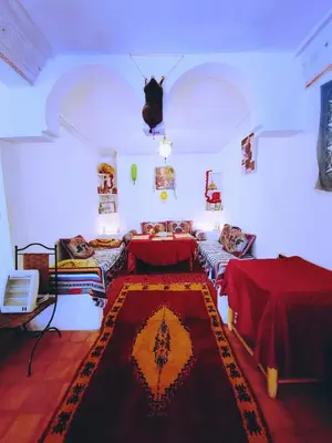a living room with two beds and a rug at Riad Kasbah des Roches in Akhendachou nʼAït Ouffi
