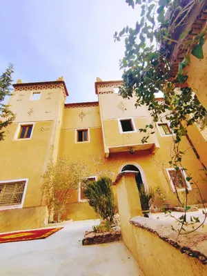 a large yellow building with a courtyard in front of it at Riad Kasbah des Roches in Akhendachou nʼAït Ouffi