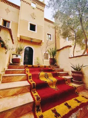 a house with a red and yellow rug on the stairs at Riad Kasbah des Roches in Akhendachou nʼAït Ouffi