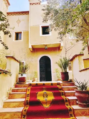 a house with a red and yellow carpet in front of a building at Riad Kasbah des Roches in Akhendachou nʼAït Ouffi