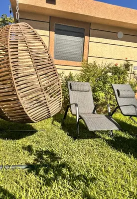 two chairs and a swing in the grass at Riad El Menzeh in Meknès