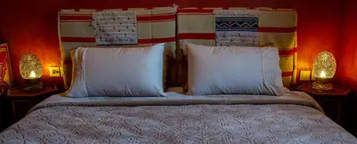 a bedroom with a bed with white pillows and two lamps at Auberge Mounia in Telouet