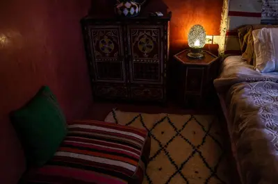 a bedroom with a couch and a dresser and a lamp at Auberge Mounia in Telouet