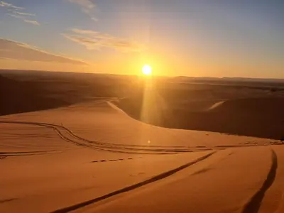 a sunset in the desert with the sun setting at lenas desert camp merzouga in Merzouga