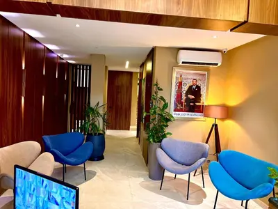 a waiting room with blue chairs and plants at Hôtel Le Manoir in Taza