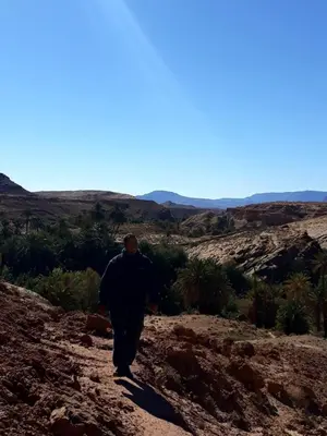 a man walking down a dirt road in the desert at Maison Ich chez Abdel in Ich