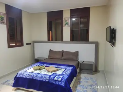 a bedroom with a bed with a blue blanket at Welcome Hôtel Dijon in Ouzoud