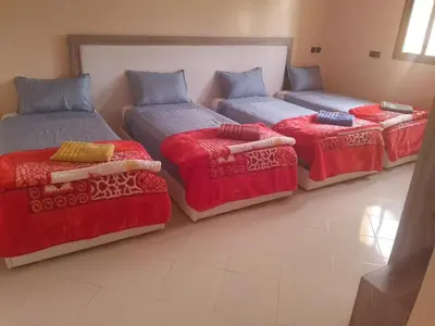 a room with three beds and a couch at Welcome Hôtel Dijon in Ouzoud