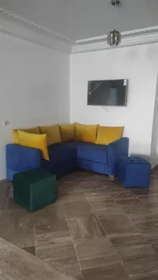 a living room with a blue couch and yellow pillows at Les Appartements de la Place Atlas in Fès
