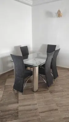 a glass table and chairs in a room at Les Appartements de la Place Atlas in Fès