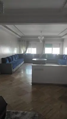 a large living room with blue couches and a table at Les Appartements de la Place Atlas in Fès