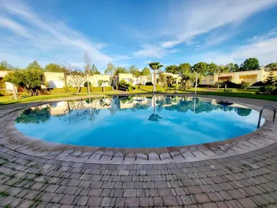 a large pool with blue water in a brick patio at Duplex Reposant avec piscine au Andalines Golf Royal Fès in Dar Ito Lahssene
