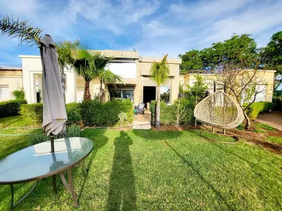a garden with a glass table and an umbrella at Duplex Reposant avec piscine au Andalines Golf Royal Fès in Dar Ito Lahssene