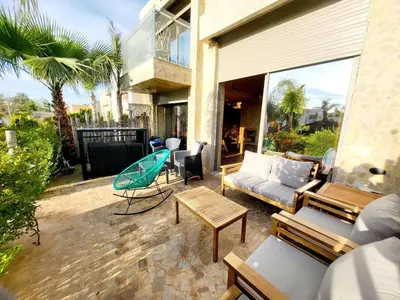 a patio with a couch and a table and chairs at Duplex Reposant avec piscine au Andalines Golf Royal Fès in Dar Ito Lahssene