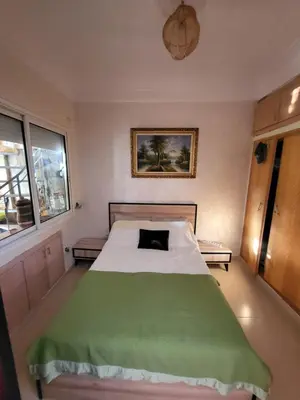 a bedroom with a bed with a green blanket at Duplex Reposant avec piscine au Andalines Golf Royal Fès in Dar Ito Lahssene
