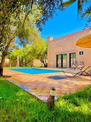 a bottle sitting in the grass next to a building at Villa des tortues 3 Marrakech piscine chaufée privative sans vis à vis in Marrakech