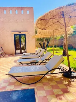 a row of lounge chairs with an umbrella at Villa des tortues 3 Marrakech piscine chaufée privative sans vis à vis in Marrakech