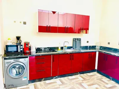 a kitchen with red cabinets and a washing machine at Villa des tortues 3 Marrakech piscine chaufée privative sans vis à vis in Marrakech
