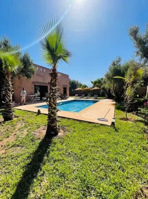 a palm tree in a yard with a swimming pool at Villa des tortues 3 Marrakech piscine chaufée privative sans vis à vis in Marrakech