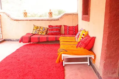a room with red and yellow pillows and a window at Gite d'étape Tafsoute in Tameskikt
