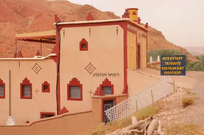 a building in the desert with a sign on it at Gite d'étape Tafsoute in Tameskikt