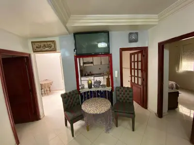 a living room with a table and chairs and a tv at apartement moderne fes in Fès