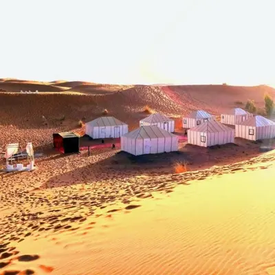 a group of tents on a beach next to a body of water at desert tribe luxury camp in Merzouga