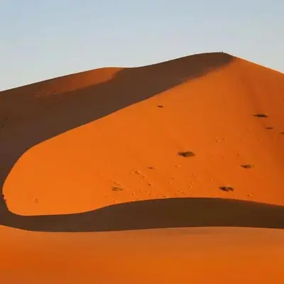 a sand dune with footprints in the desert at desert tribe luxury camp in Merzouga