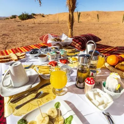a picnic table in the desert with food on it at desert tribe luxury camp in Merzouga