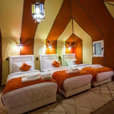 two beds in a room with a large mirror at desert tribe luxury camp in Merzouga