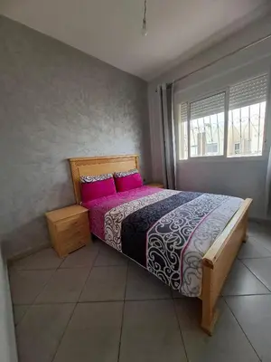 a bedroom with a large bed with pink pillows at Appartement à côté de Kitea route de Sefrou in Fès