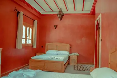 a bedroom with two beds in a room with red walls at Riad Restaurant MARZOUK in Aït Baha