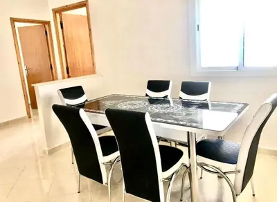 a dining room table with black and white chairs at Modern apartment Hamria Meknes in Meknès