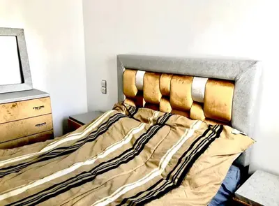 a bed in a bedroom with a wooden headboard at Modern apartment Hamria Meknes in Meknès