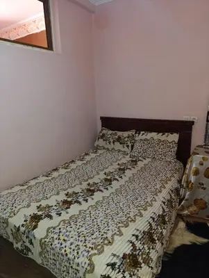 a bed in a bedroom with a comforter on it at Tradionelle Berber Ain Sardoun in Beni Mellal