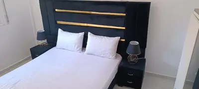 a bed with a black headboard and white sheets and pillows at maison soleil in Ifrane