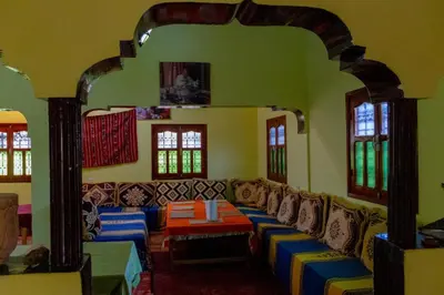 a living room with couches in a room with windows at Kasbah Les Nomades in Skoura