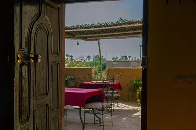 a table and chairs with a red table cloth on a balcony at Kasbah Les Nomades in Skoura