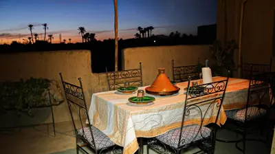 a table with a tea pot and chairs on a patio at Kasbah Les Nomades in Skoura