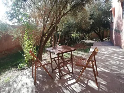 a table and two chairs sitting next to a tree at Dâr Mâbâ in Tazenakht