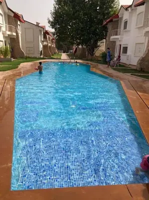 a large blue swimming pool with a child in it at Chalet Villa de Luxe - Piscine in Dchar Aït Belkassem