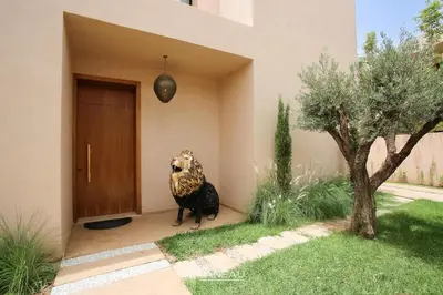 a statue of a dog sitting next to a door at Villa de standing piscine à débordement à 15 min de Marrakech in Ourika