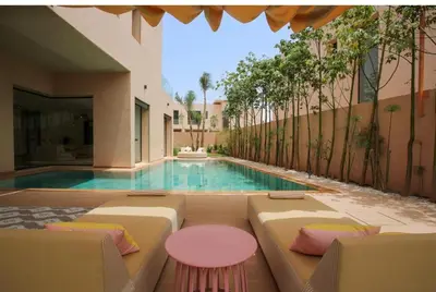 a swimming pool with chairs and a pink table at Villa de standing piscine à débordement à 15 min de Marrakech in Ourika