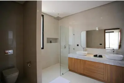 a bathroom with two sinks and a shower and a mirror at Villa de standing piscine à débordement à 15 min de Marrakech in Ourika