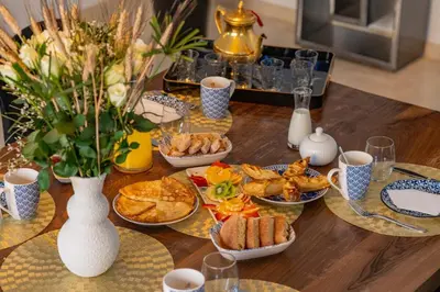 a wooden table topped with plates of food and cups at Villa de standing piscine à débordement à 15 min de Marrakech in Ourika