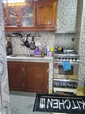 a small kitchen with wooden cabinets and a stove at إقامة شاكر in Meknès