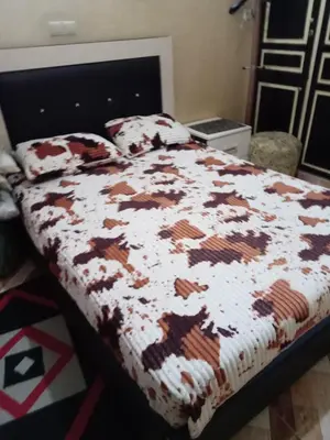 a bedroom with a bed with a brown and white comforter at إقامة شاكر in Meknès