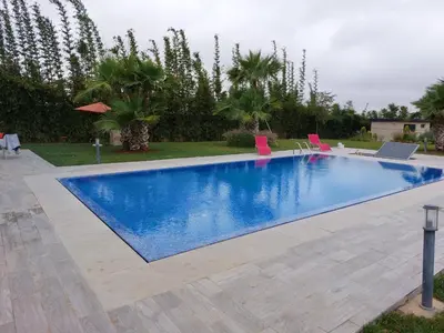 a swimming pool in a yard with pink chairs at Domaine Farah in Meknès