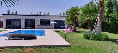 a house with a swimming pool and palm trees at Domaine Farah in Meknès