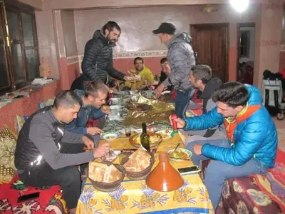 a group of people sitting around a table with food at gîte taghia ahansal in Taghia